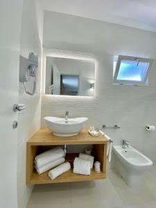 a white bathroom with a sink and a mirror at Sirena Suite Deluxe in Peschici
