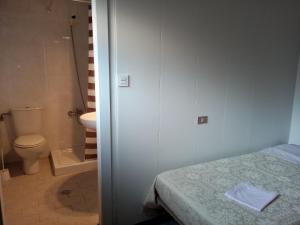 uma casa de banho com uma cama, um WC e um chuveiro em Pensión ** Abacá Gijón em Gijón