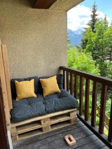 a couch on a porch with a view of the mountains at Studio Montagne - Plein Soleil et Terrasse in Briançon