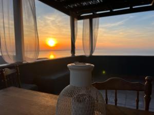 um vaso sentado numa mesa em frente a um pôr-do-sol em Villa Esmeralda Kea em Fotimárion