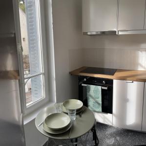 una pequeña cocina con una mesa con dos platos. en Charmant studio proche RER B direction Paris, en Fontenay-aux-Roses