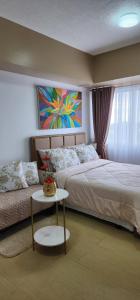 a bedroom with a bed and a table and a painting at Studio Unit for Family @ Aspira in Cagayan de Oro