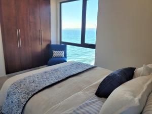 a bedroom with a bed and a blue chair at Beachfront Luxury Seaside Condo + Pool & Jacuzzi in Rosarito