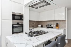 a kitchen with white cabinets and a stove top oven at Richmond Riverside in Richmond upon Thames +25 photos