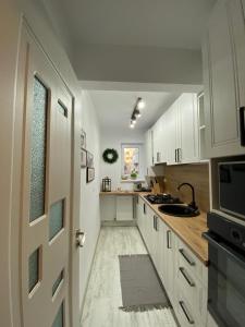 a kitchen with white cabinets and a sink and a door at ULO Residence in Alba Iulia