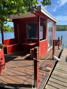 a red cabin on a dock next to the water at Floß Casanova in Erkner