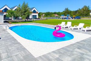 a swimming pool with a pink swan in the water at Słońce i Woda Domki Całoroczne, Podgrzewany Basen, Balia z jacuzzi, Starlink Internet, Klimatyzacja, Bezpłatny Parking in Łeba