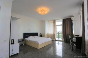 Schlafzimmer mit einem Bett, einem Tisch und einem Fenster in der Unterkunft Hotel CARLEONE in Batumi