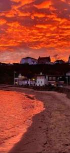 a sunset over a beach with houses and the ocean at The Holiday Hoose in Kinghorn
