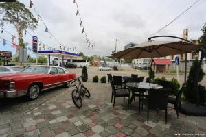 una macchina rossa parcheggiata accanto a un tavolo con una bicicletta di Hotel CARLEONE a Batumi