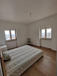 - une chambre blanche avec 2 lits et 2 fenêtres dans l'établissement Portas da Vila, à Sesimbra