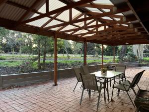 a patio with a table and chairs under a wooden pergola at Wandjoo Cottage Cranbourne in Lyndhurst South