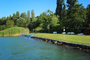 a river with a dock in the middle of a park at Aquilo Hotel Panoráma in Tihany