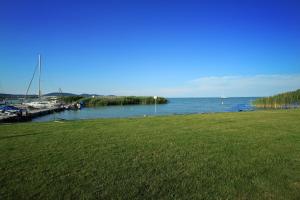 a grassy field next to a marina with boats in the water at Aquilo Hotel Panoráma in Tihany