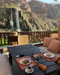a table with food on it with a waterfall in the background at Ma'in Hot Springs in Sowayma