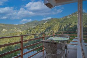 einen Tisch und Stühle auf einem Balkon mit Aussicht in der Unterkunft Wood crista retreat Kufri Open air Terrace in Kūfrī