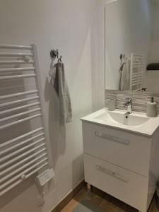 a white bathroom with a sink and a mirror at La Petite Perle in Andernos-les-Bains