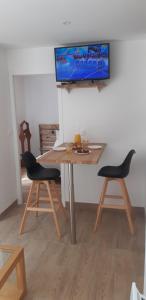 昂代爾諾萊班的住宿－La Petite Perle，一张桌子、两把椅子和墙上的一台电视