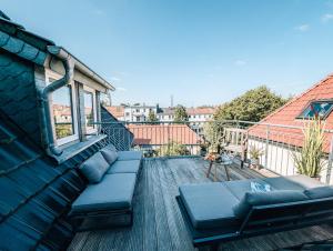 uma varanda com um sofá e uma mesa num edifício em 4-Schlafzimmer-Terrassensuite Oasis - WORKSPACE EM-APARTMENTS DEUTSCHLAND em Bielefeld