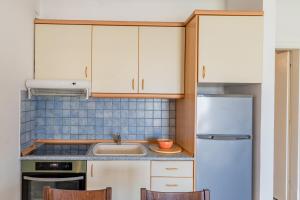 uma cozinha com armários brancos, um lavatório e um frigorífico em Erifili House em Kallithea Halkidikis