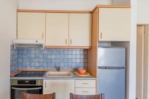 a kitchen with white cabinets and a sink and a refrigerator at Erifili Kallithea in Kallithea Halkidikis
