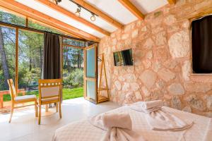 a bedroom with a stone wall with a bed and a tv at Casa De Sherys in Kas