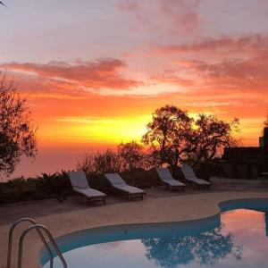 un grupo de sillas sentadas junto a una piscina con puesta de sol en Bouganville-La Casa Dei Fiori, en Pantelleria