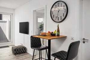 ein Esszimmer mit einem Tisch und einer Uhr an der Wand in der Unterkunft Park Avenue Apartments I Domsuite I Hbf I Netflix I WLAN in Köln