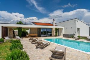 - une piscine avec des chaises et une maison dans l'établissement Villa T, spacious with heated pool & jacuzzi, à Raštević