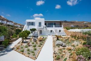 una casa bianca con un giardino di fronte di Vaqueros a Mykonos Città