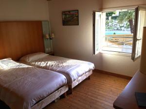 - 2 lits dans une chambre d'hôtel avec fenêtre dans l'établissement Hôtel Mer et Forêt, à Saint-Trojan-les-Bains