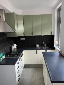 a kitchen with white cabinets and a black counter top at Slapen bij Bartje in Assen