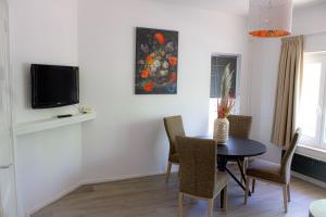 a dining room with a table and chairs and a tv at Slapen bij Bartje in Assen