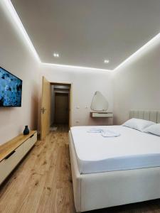 a bedroom with a large white bed and a wooden floor at Beach Apartaments Durres in Durrës