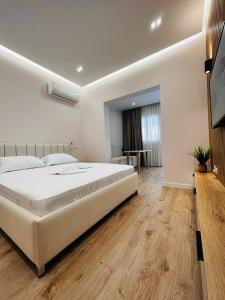 Un dormitorio con una gran cama blanca y una mesa en Beach Apartaments Durres, en Durrës