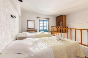 Habitación con 3 camas y espejo. en Joanna Apartments, en Agia Pelagia