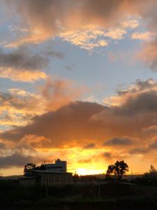 a cloudy sky at sunset with a building in the foreground at Kitnet Europa in Bonito