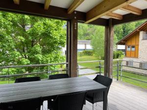 porche de madera con mesa y sillas en la cubierta en Wunderschöne Wohnung am See mit Sauna & Whirlpool en Unterterzen