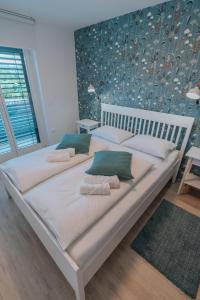 1 dormitorio con 1 cama blanca grande con almohadas verdes en APARTMA LAMBERGER, en Žirovnica