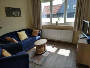 a living room with a blue couch and a table at Haus Waldblick in Hohegeiß