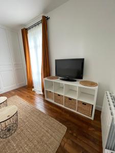 un salon avec une télévision sur un meuble blanc dans l'établissement Charmant studio proche RER B direction Paris, à Fontenay-aux-Roses