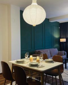 un tavolo con sedie e un lampadario a braccio in soggiorno di Zen Apartments Pejë a Pejë