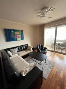uma sala de estar com um sofá de couro preto e uma mesa em b-612 em Petrovac na Moru
