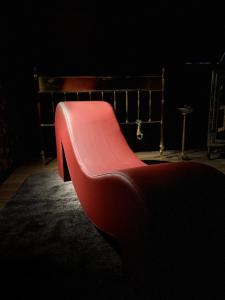 - un canapé rouge dans une pièce sombre dans l'établissement Amour Amour Love Room, à Penvénan