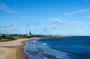 a view of a beach with a church in the distance at AzZule Apartments in Tynemouth
