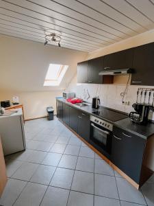 a kitchen with black cabinets and a white tile floor at Ferienwohnung 2 in Dargen