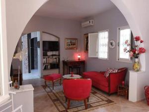 a living room with a red couch and a table at Chambre d'hôtes, Dar l'air du temps in Aghīr