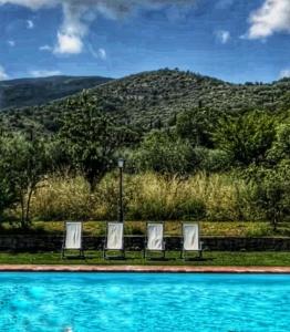 - deux chaises assises à côté de la piscine dans l'établissement Relais Villa Baldelli, à Cortone