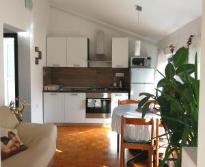 eine Küche mit weißen Schränken und einem Tisch in einem Zimmer in der Unterkunft MILLENCA Apartment in Izola