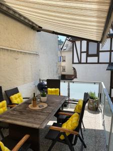 a patio with a wooden table and yellow cushioned chairs at Ferienhaus Ankerpunkt in Zell an der Mosel